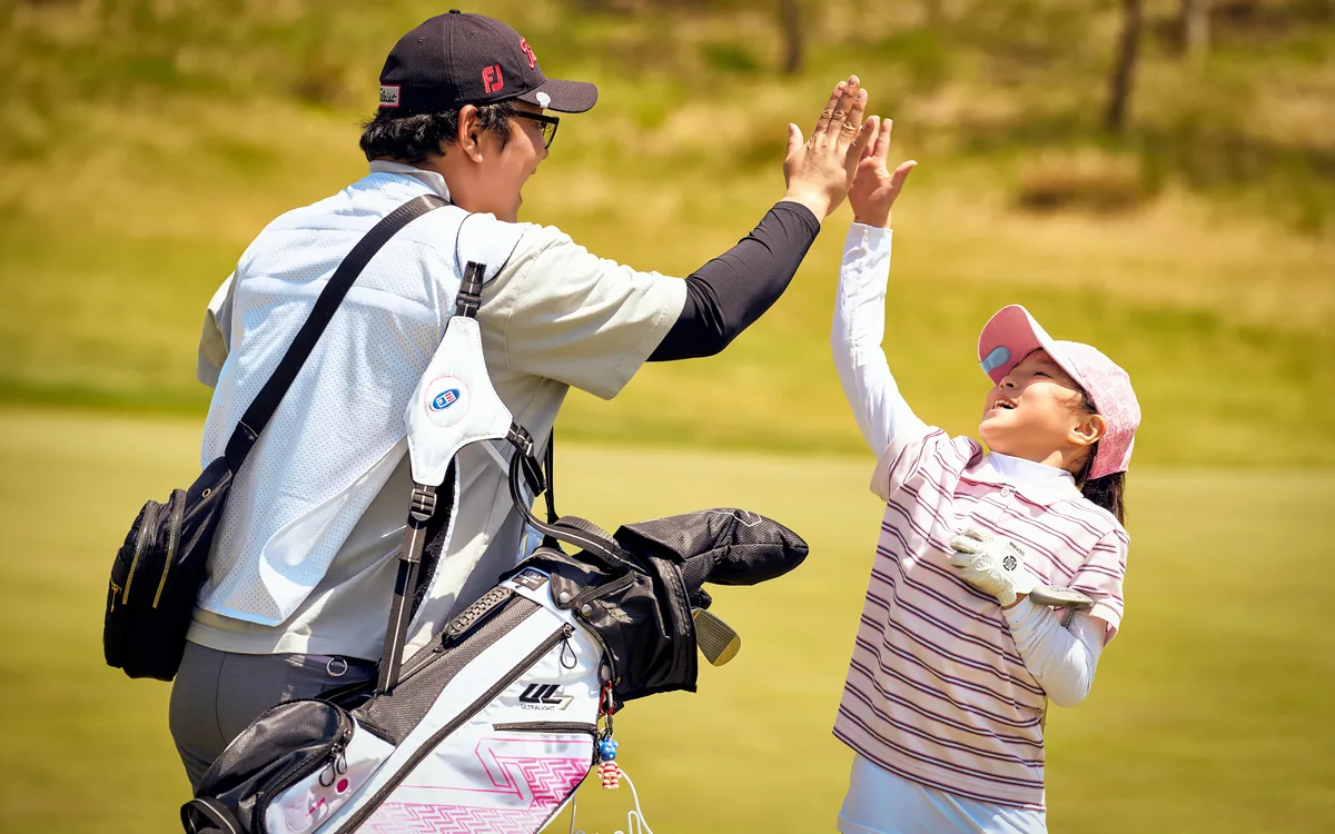 Junior golfer and caddie celebrating a hole